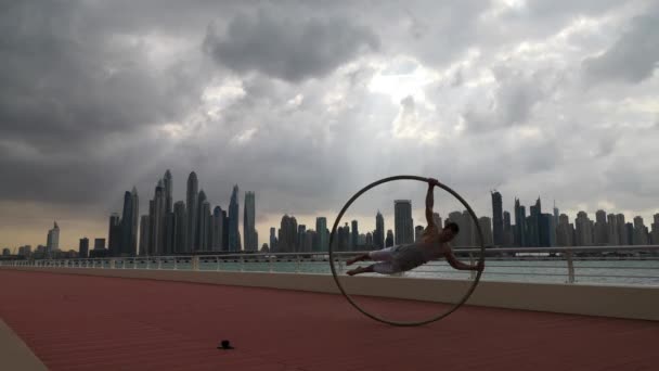 Cyr Wheel umělec s cityscape pozadí Dubaje během západu slunce — Stock video