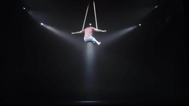 4k Muscular circus aerialist on the aerial straps in black studio — Stock Video