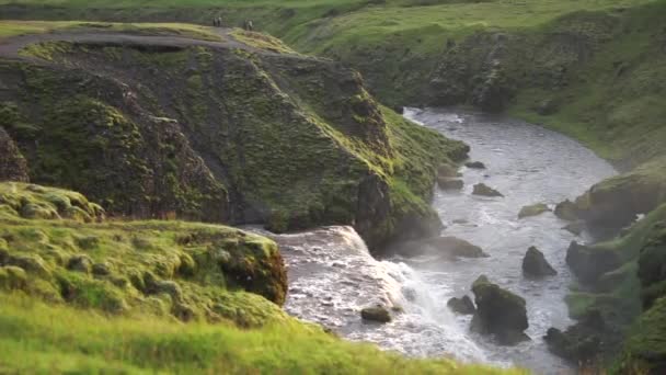 Медленное движение красивой гладкой реки в Исландии, окруженной зелеными горлышками во время заката на пешеходной тропе Fimmvorduhals недалеко от Скогара — стоковое видео