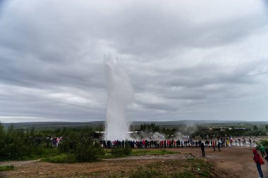İzlanda 'daki Strokkur gayzeri turistler bakarken patlıyor. Strokkur, İzlanda - 30 Temmuz 2019: İzlanda 'daki Strokkur gayzeri turistler arasında patlıyor.