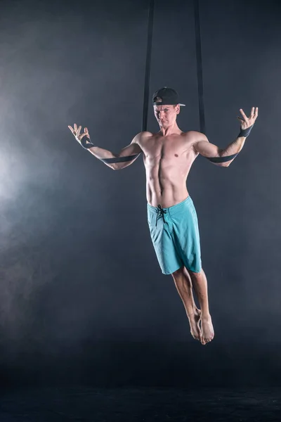 Circus καλλιτέχνης στις εναέριες τιράντες με ισχυρούς μυς σε μαύρο φόντο φορώντας casual ρούχα — Φωτογραφία Αρχείου