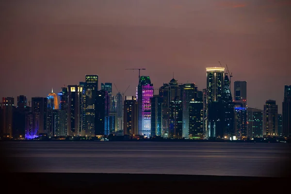 Vibrante horizonte de Doha por la noche visto desde el lado opuesto de la bahía de la capital puesta de sol — Foto de Stock