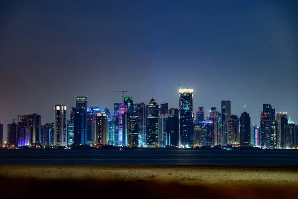 Vibrant Skyline of Doha at Night as seen from the opposite side of the capital city bay sunset.
