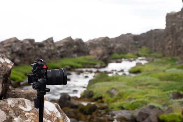 Photo camera on the tripod with blurred river on background
