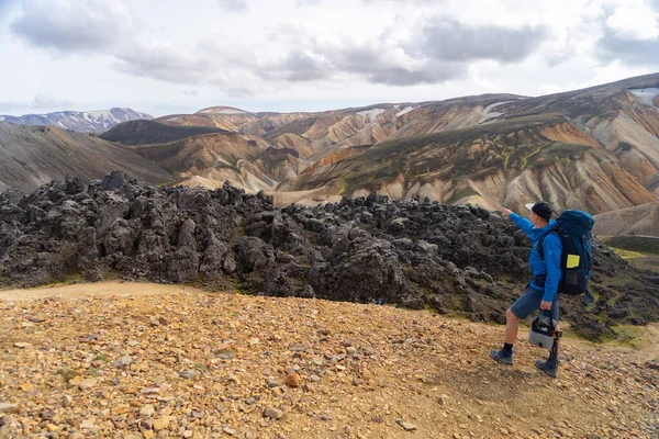Caminante con mochila en el valle de Landmannalaugar. Islandia. Montañas coloridas en el sendero de senderismo Laugavegur. La combinación de capas de rocas multicolores, minerales, hierba y musgo — Foto de Stock