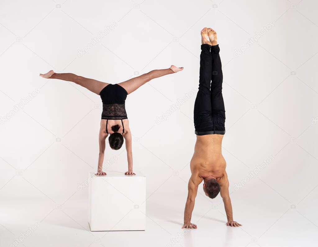 Good shaped man and woman practicing handstand exercise isolated on white background. Strength and motivation