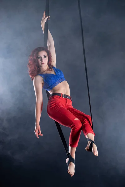 Kvinnlig atletisk, sexig och flexibel antenn cirkusartist med rödhårig på antenn remmar på svart bakgrund — Stockfoto