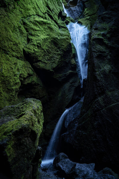 A waterfall near the mossy rocks in early summer.