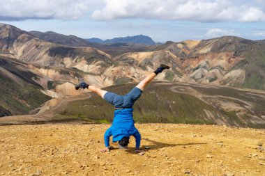 Landmannalaugar Vadisi 'nde elinde yürüyen bir yürüyüşçü. İzlanda. Laugavegur yürüyüş yolunda renkli dağlar. Çok renkli kaya, mineral, ot ve yosun katmanlarının birleşimi