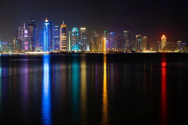 Vibrante horizonte de Doha por la noche visto desde el lado opuesto de la bahía de la capital por la noche — Foto de Stock