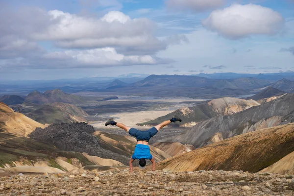 Caminante de pie sobre su mano en el valle de Landmannalaugar. Islandia. Montañas coloridas en el sendero de senderismo Laugavegur. La combinación de capas de rocas multicolores, minerales, hierba y musgo — Foto de Stock