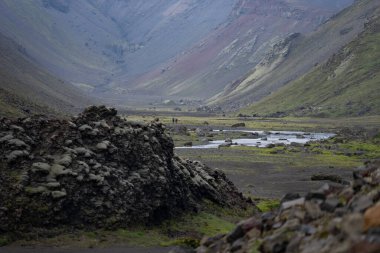İzlanda dağlarında yosun kaplı Eldgja Kanyonu 'ndan geçen iki yürüyüşçü.