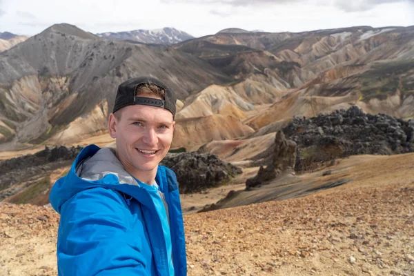 Sırt çantalı gezgin Landmannalaugar Vadisi 'nde selfie çekiyor. İzlanda. Laugavegur yürüyüş yolunda renkli dağlar. Çok renkli kaya, mineral, ot ve yosun katmanlarının birleşimi — Stok fotoğraf