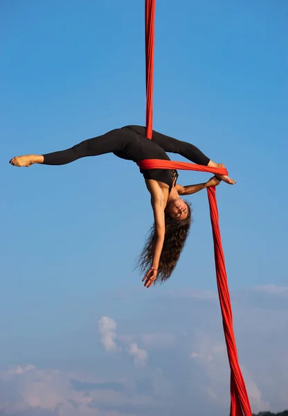 Bella e flessibile artista del circo femminile che balla con seta aerea su sfondo cielo — Foto Stock