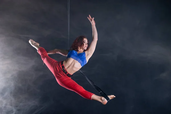 Kvinnlig atletisk, sexig och flexibel antenn cirkusartist med rödhårig på antenn remmar på svart bakgrund — Stockfoto