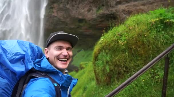 Turista feliz tomando selfie con hermosa cascada de Seljalandsfoss en el fondo. Concepto de viaje y estilo de vida saludable . — Vídeos de Stock