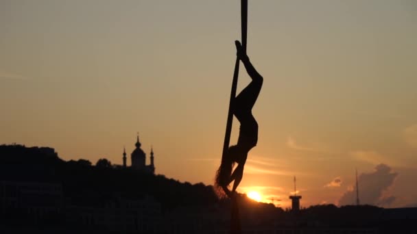 Sylwetka elastycznej kobiety Acrobat na antenę jedwabiu podczas zachodu słońca na tle Kijowa miasta. pojęcie wolności i pokoju — Wideo stockowe