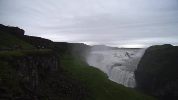 A turisták hosszú sora a Gullfoss vízeséshez a felhős napon. Izland. Lassú mozgás — Stock videók