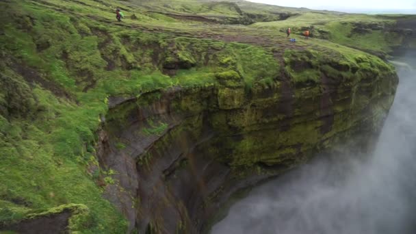 아이슬란드 의아름다운 완만 한 폭포 가 낮에 천천히 움직 이는 등산 로를 따라 달리고 있다 — 비디오
