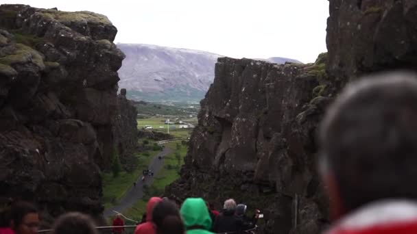 Iceland - July 2018: Many tourists walking on the lower trail sandwiched between the broken-apart cliffs at Thingvellir national park — Wideo stockowe