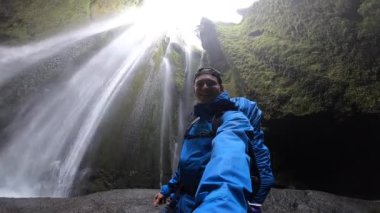 Turistik güçlü şelaleyi keşfeden gezgin mağarada Gljufrabui, yavaş çekim, İzlanda