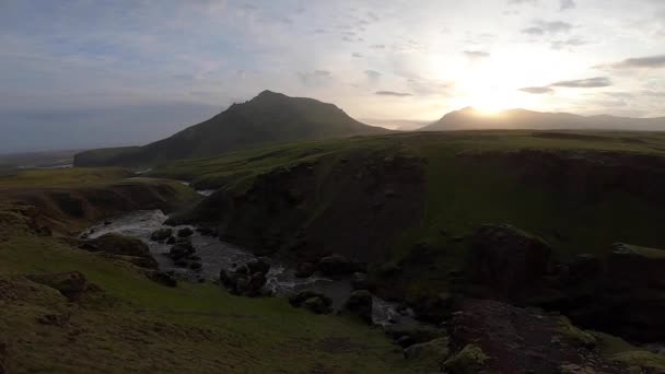 Гарна гладка річка в Ісландії, оточена зеленими пагорбами під час заходу сонця на Фімвордуальських пішохідних стежках поблизу Скогара. — стокове відео