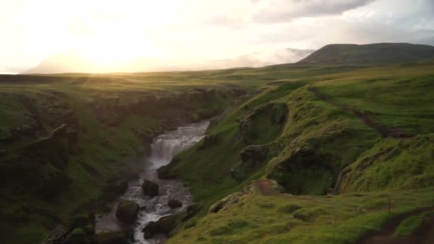Mouvement lent de la belle rivière lisse en Islande entourée de collines verdoyantes pendant le coucher du soleil sur le sentier de randonnée Fimmvorduhals près de Skogar 