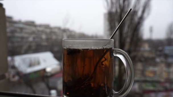 Чашка гарячого чаю на денному світлі засніжений міський пейзажний фон у повільному русі — стокове відео