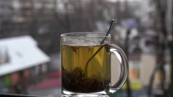 Чашка горячего чая на дневном снежном фоне городского пейзажа — стоковое видео
