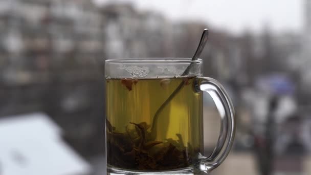 Tasse de thé chaud sur le fond de paysage urbain enneigé lumière du jour — Video