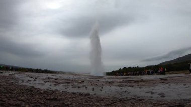 İzlanda 'daki Strokkur gayzeri turistler bakarken patlıyor. Strokkur, İzlanda - 30 Temmuz 2019: İzlanda 'daki Strokkur gayzeri turistler arasında patlıyor.