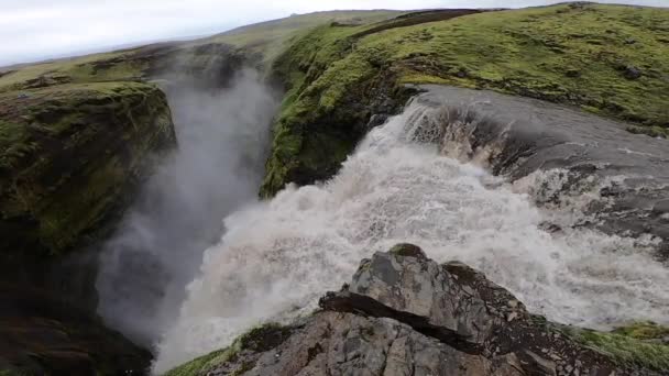 Hermosa cascada poderosa en cámara lenta rodeada de verdes colinas durante la puesta de sol en el sendero de senderismo Fimmvorduhals cerca de Skogar. Islandia — Vídeo de stock