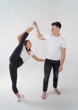 Kadın jimnastik yaparken ikiye bölünmüş ve adam elinde içecekle bardağın yanında duruyor. Sağlıklı yaşam tarzı ve yaratıcılık kavramı 