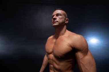 Siyah arka planda kaslı bir adam var. Güçlü erkek çıplak gövde kasları