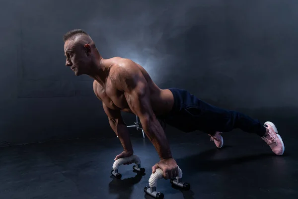 Hombre muscular haciendo ejercicio calisténico aislado sobre el fondo negro —  Fotos de Stock