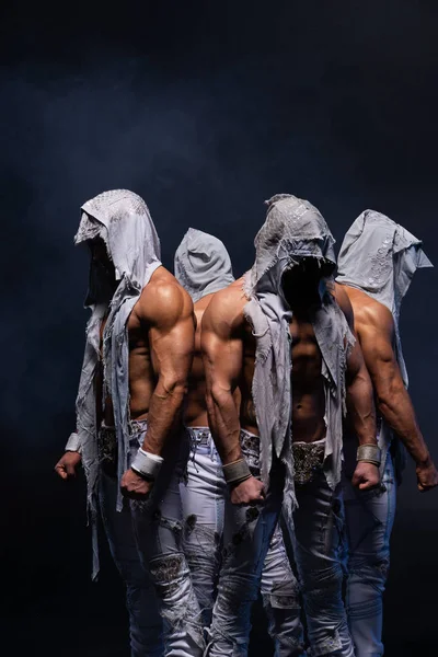 Quatro homens góticos musculosos de pé sem camisa sobre fundo preto. Conceito de mistério e segredo — Fotografia de Stock
