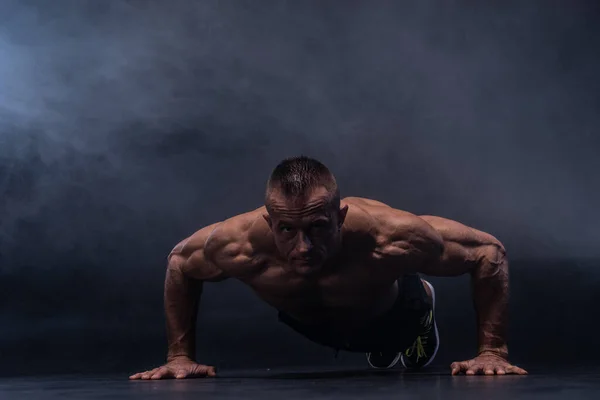 Muskulöser Mann bei kalisthenischen Übungen isoliert auf schwarzem Hintergrund — Stockfoto