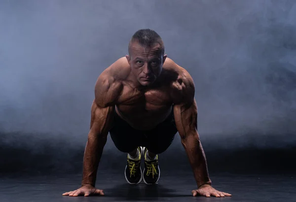Hombre muscular haciendo ejercicio calisténico aislado sobre el fondo negro —  Fotos de Stock