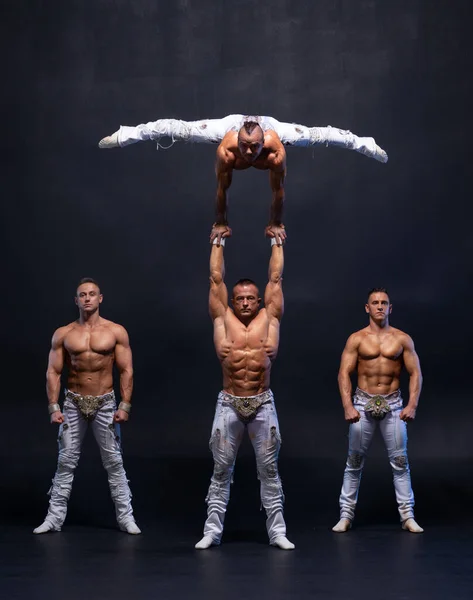 Quatro muscular homem executar difícil acrobático truques no preto estúdio — Fotografia de Stock