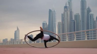 Günbatımında Dubai 'nin arka planında siyah beyaz şık kıyafetler giyen Cyr Wheel sanatçısı
