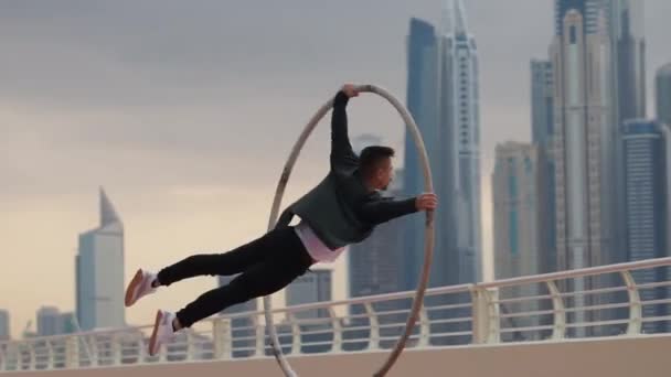 Cyr Wheel artysta robi sztuczki slow motion noszenie czarno-białe inteligentne ubrania z tłem krajobraz Dubaju podczas zachodu słońca — Wideo stockowe