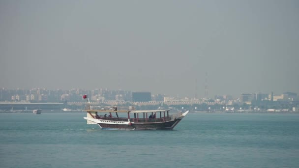 Barco histórico retro con vista panorámica borrosa del horizonte moderno de Doha y palmeras verdes en el fondo — Vídeos de Stock