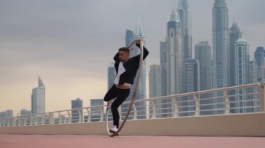 Günbatımında Dubai 'nin arka planında siyah beyaz şık kıyafetler giyen Cyr Wheel sanatçısı