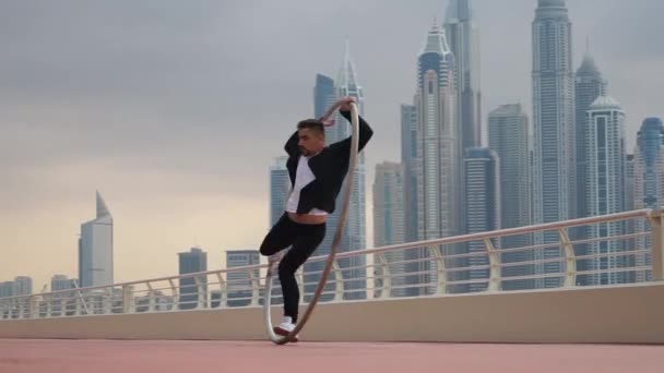 Cyr Wheel artista vestindo roupas inteligentes em preto e branco com fundo cityscape de Dubai durante o pôr do sol — Vídeo de Stock