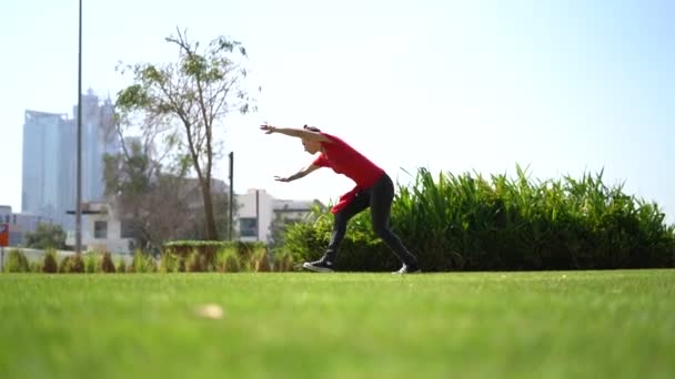 Young woman jumping high performing acrobatic on the green grass outdoors in Dubai city — Stock Video