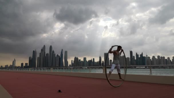 Cyr Wheel artysta z tłem miasta Dubaju podczas zachodu słońca — Wideo stockowe