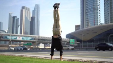 Akrobat bir elinde bulanık Dubai şehir manzarası ile dengesini koruyor. Modern ve sağlıklı yaşam tarzı kavramı.