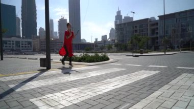 Dubai 'nin arka planında ağır çekimde yaya geçidinden atlayan genç bir kız.