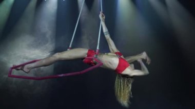 Sahnede, arka planda spot ışıkları olan ince ve seksi kadın hava akrobatları var. 