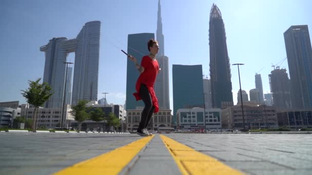 Mladá dívka skákání s švihadlem s cityscape pozadí Dubaje ve zpomaleném filmu — Stock video